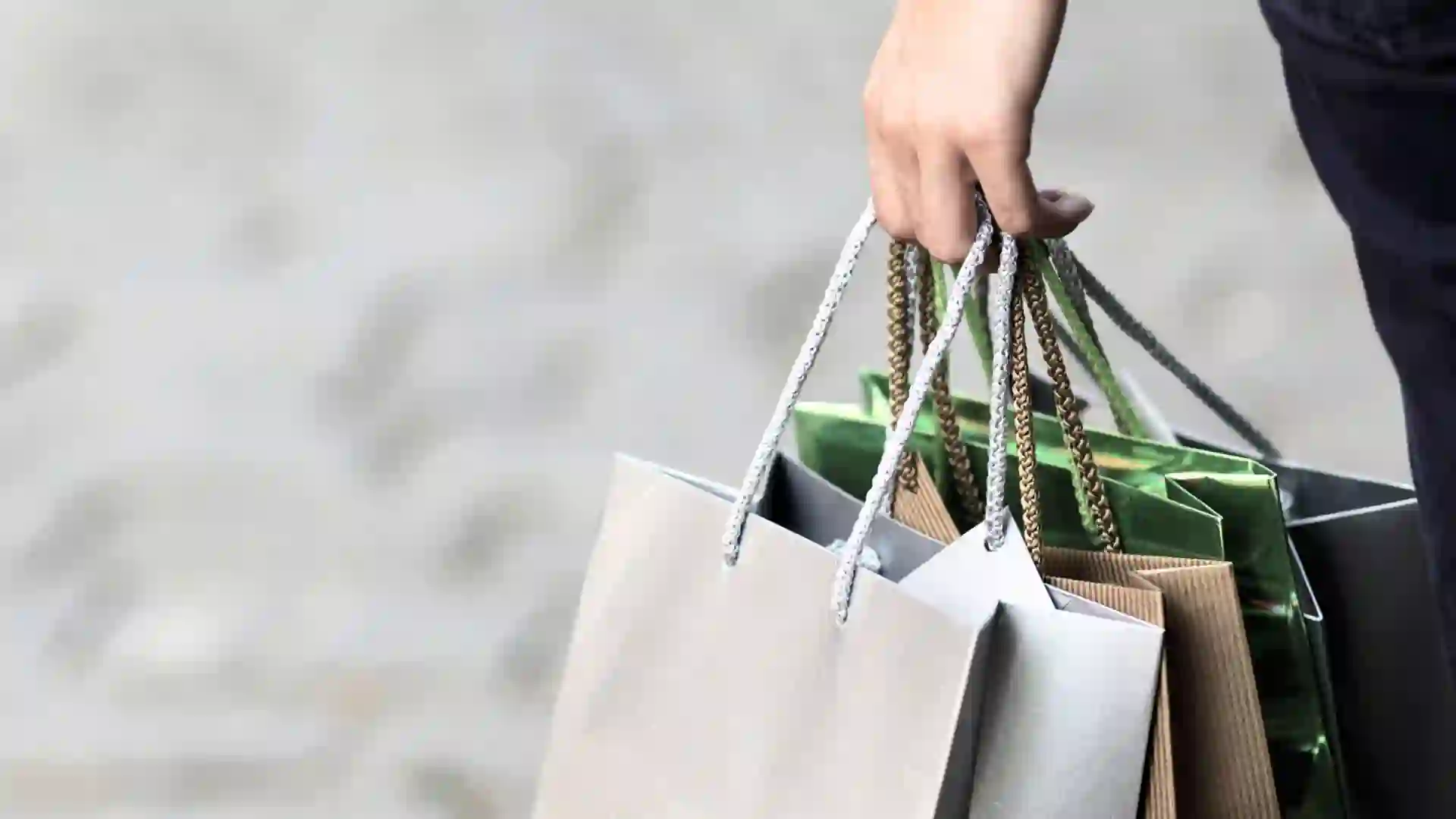 Person hält verschiedene Einkaufstaschen.