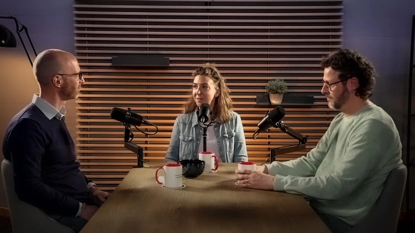 Interveiwsetting mit zwei Personen die sich gegenüber sizen und einer fragenden Person in der Mitte.